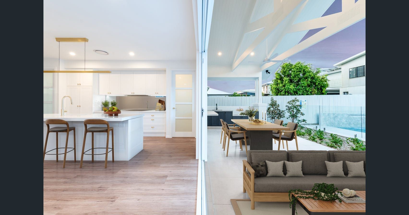 Open-plan kitchen and living room opening to a patio with outdoor seating and greenery