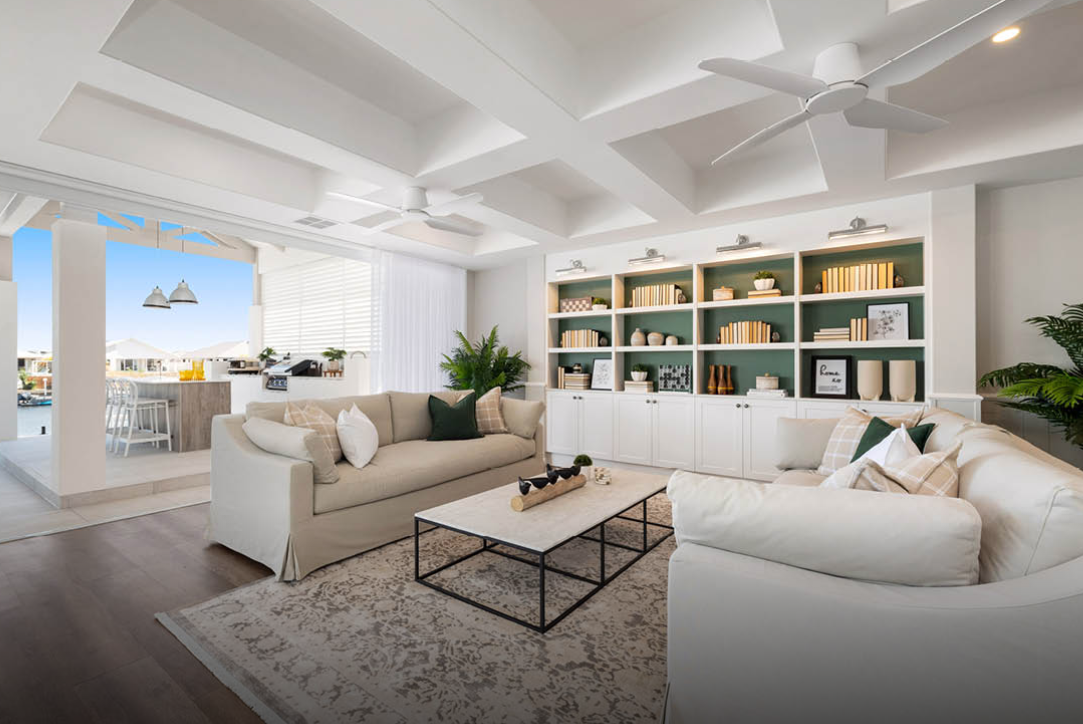 Bright modern living room with white sofas, a coffee table, and built-in shelves by large windows.