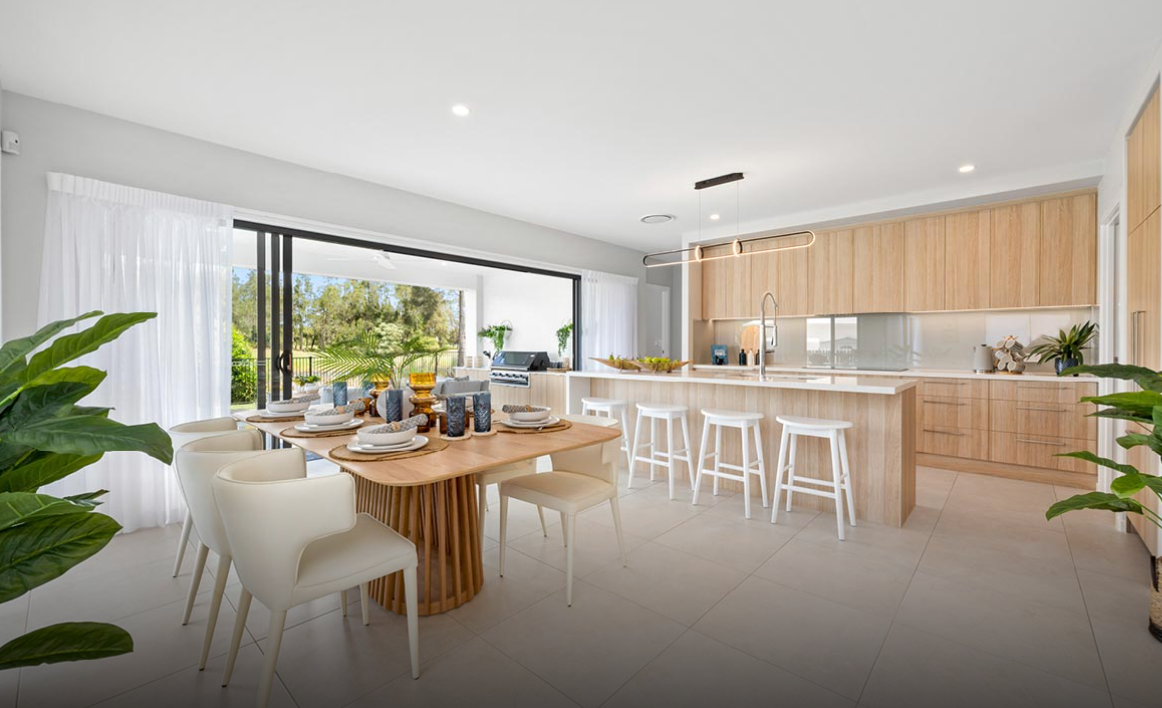 Bright modern kitchen and dining area with wood cabinets, white chairs, and large sliding glass doors