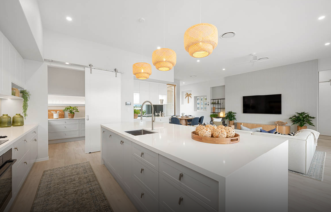 Bright modern kitchen with white island, woven pendant lights, and open living area