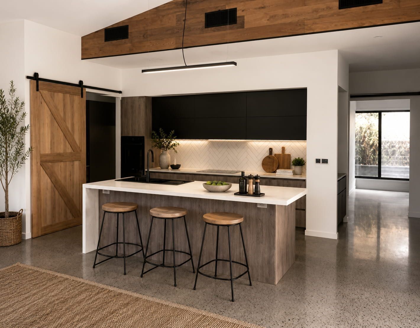 Modern kitchen with wood island, three stools, black backsplash, and barn-style sliding door