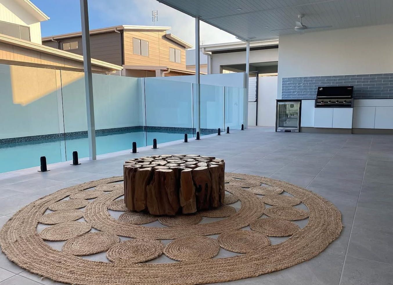 Modern patio with pool, circular stone fire pit, pergola, and built-in grill area