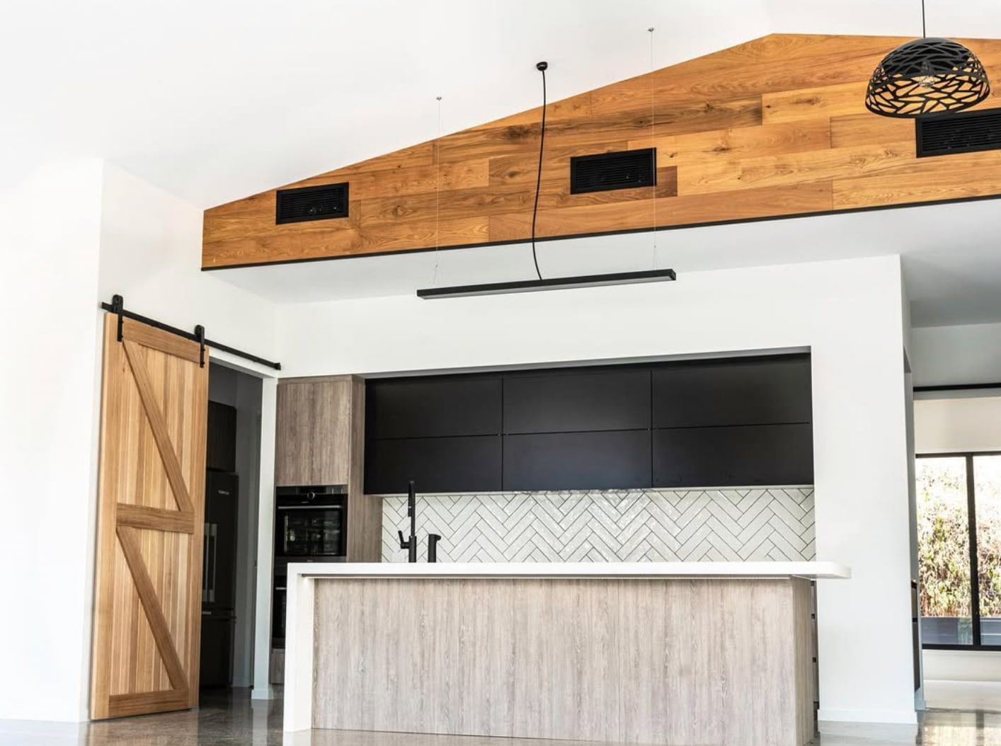 Modern kitchen with wood island, black cabinets, and vaulted wood ceiling
