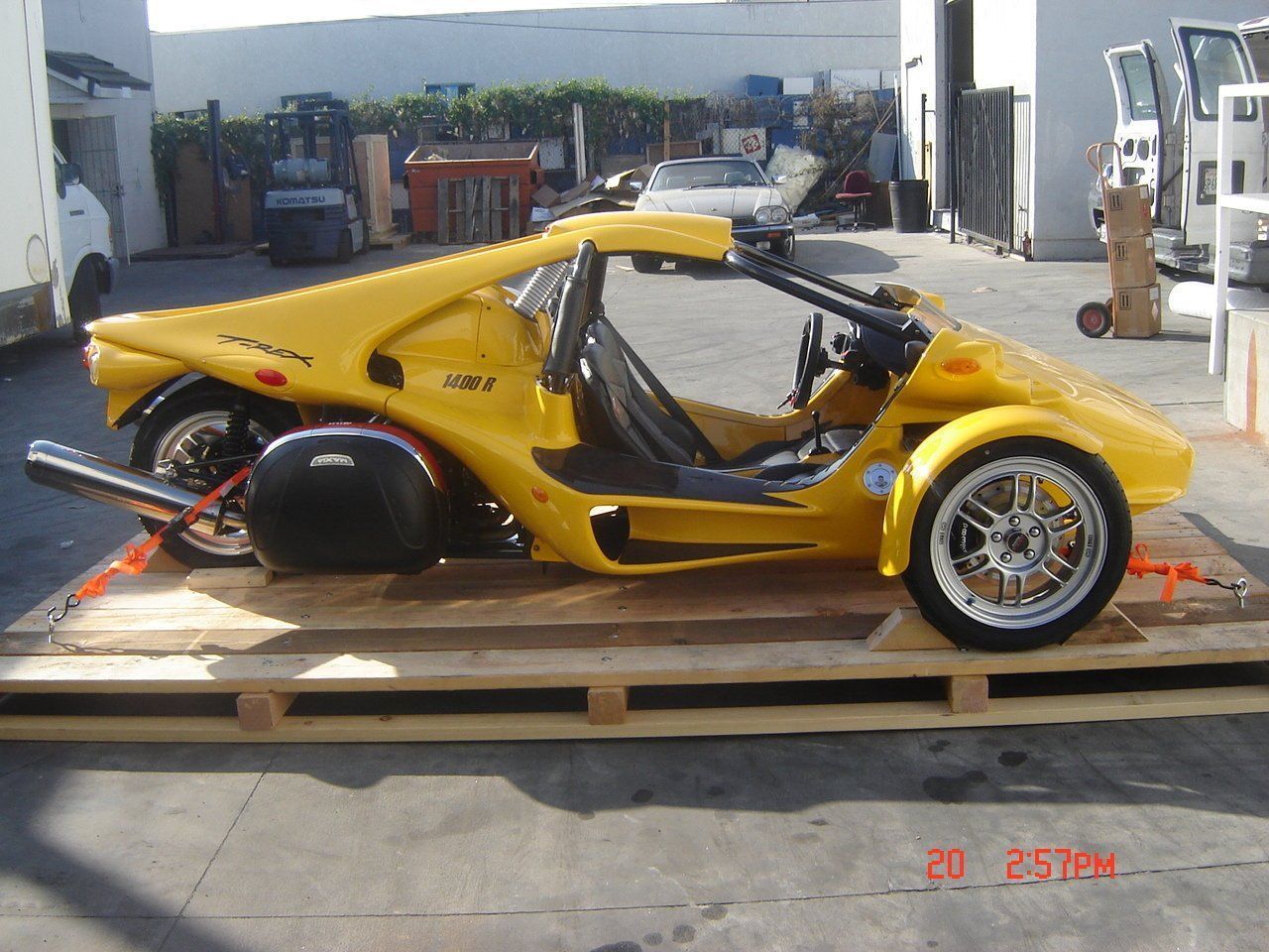 Yellow three-wheeled vehicle on wooden pallet, outdoors. Yellow three-wheeled vehicle on wooden pallet, outdoors.