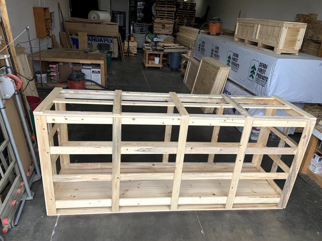Wooden crate frame with shelves, in a workshop setting.