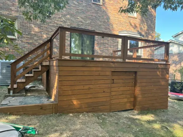 Wooden backyard deck with stairs and railing attached to a brick house