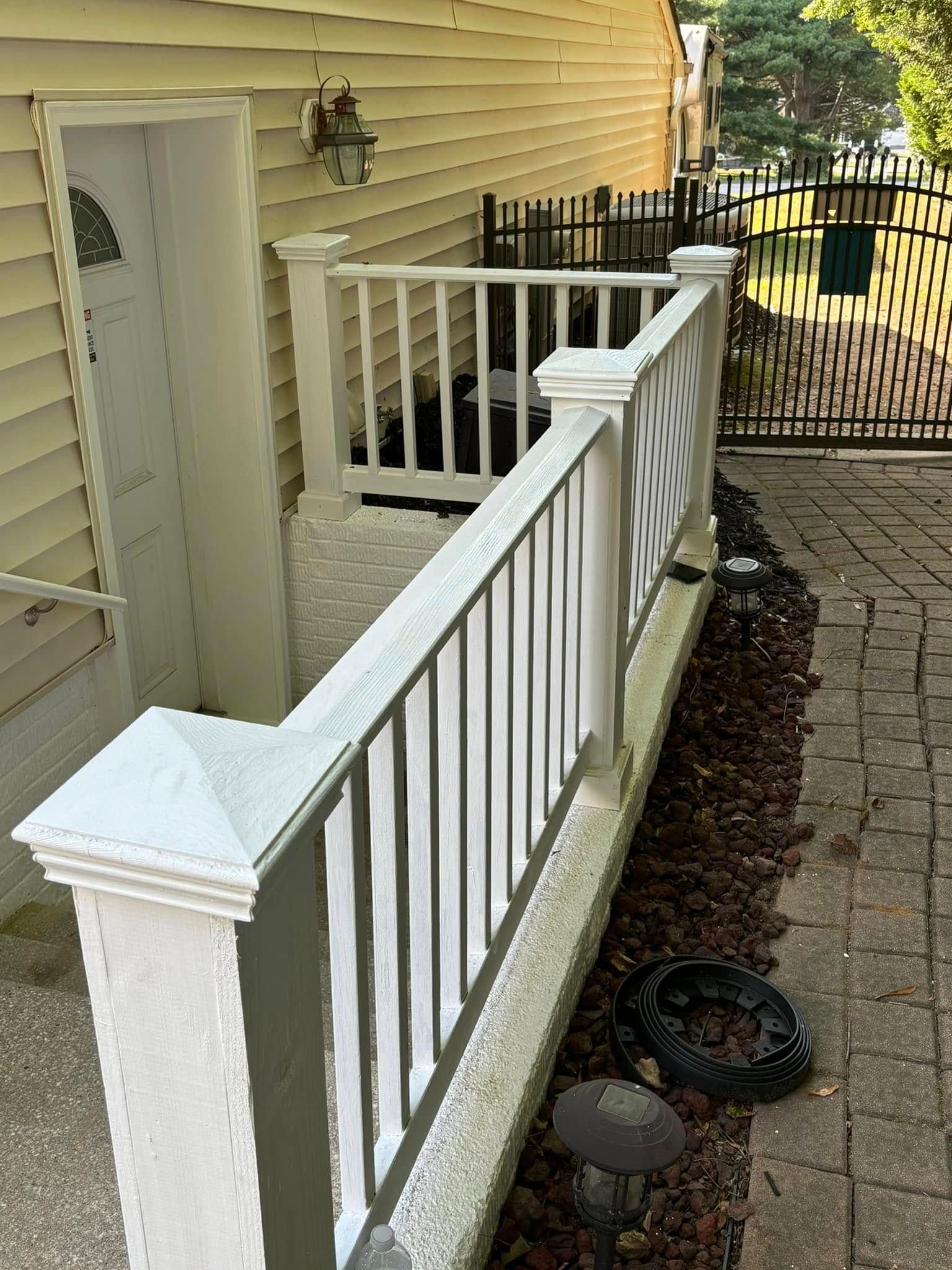 Narrow white-railed ramp beside a beige house, leading to a fenced backyard path.