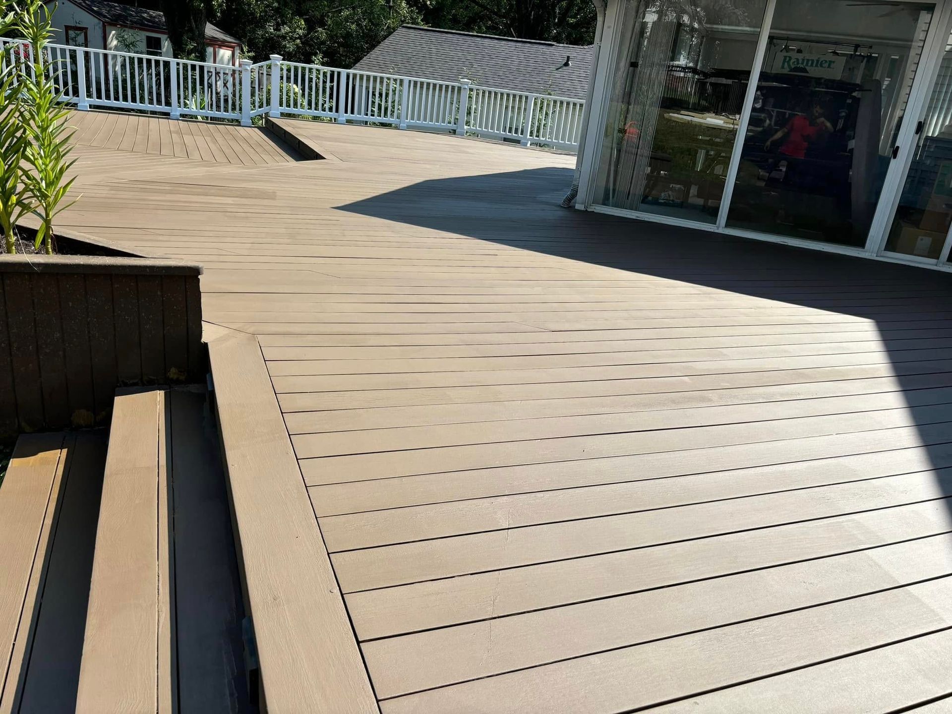 Wooden boardwalk with railings and a shaded building entrance on a sunny day