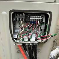 Open electrical control box with exposed red, green, and black wires and terminal blocks