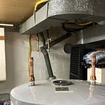 Water heater with two exposed copper pipes and ductwork in a utility closet.