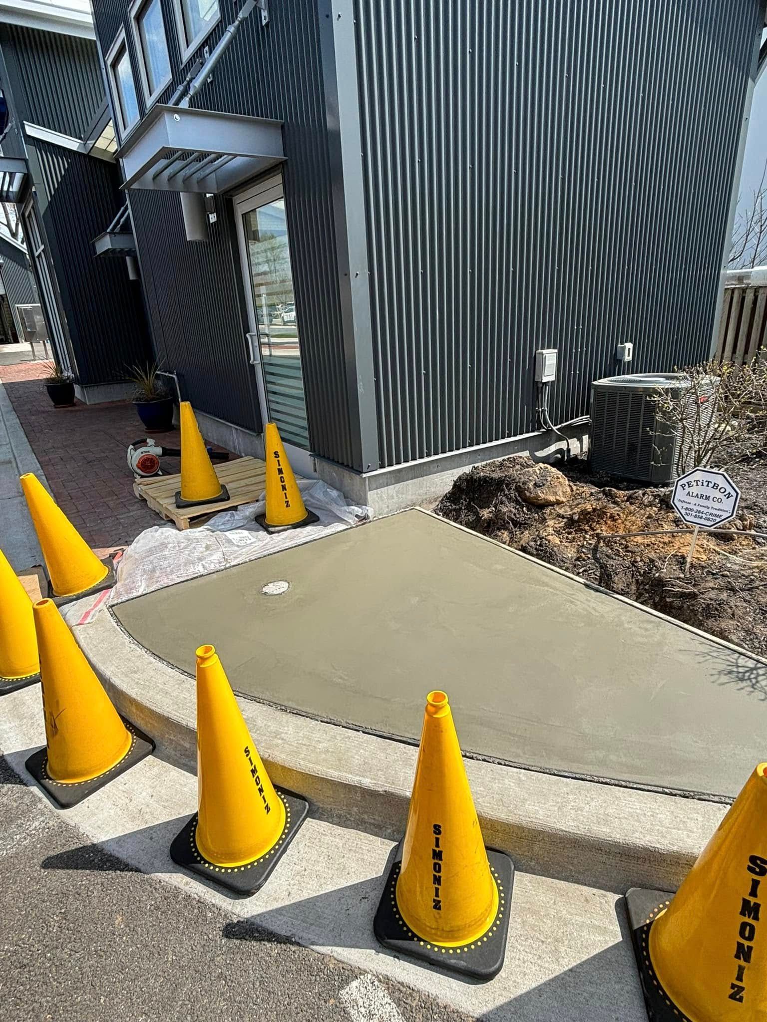 Walkway bordered by yellow cones beside a black-and-white striped building entrance.