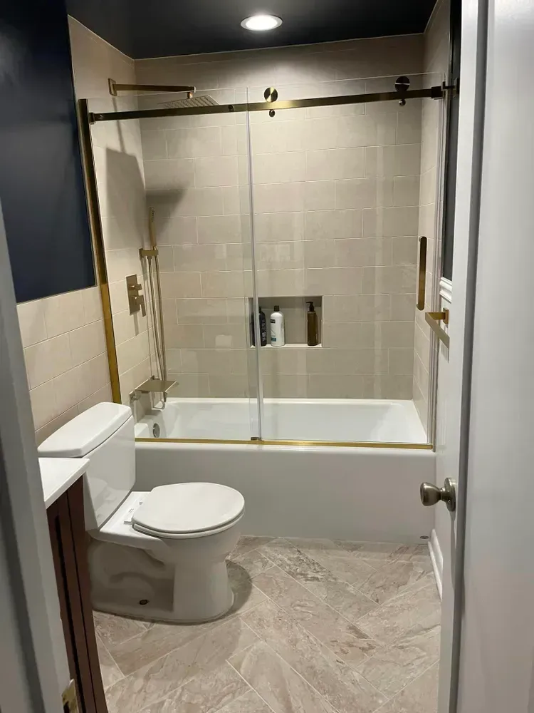 Bathroom with toilet, bathtub-shower combo, and beige tile flooring.