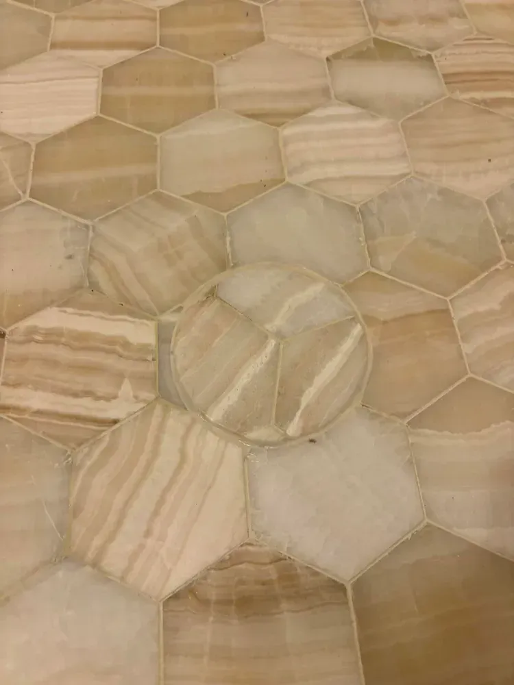 Beige and tan hexagonal stone floor tiles with natural wood-like veining