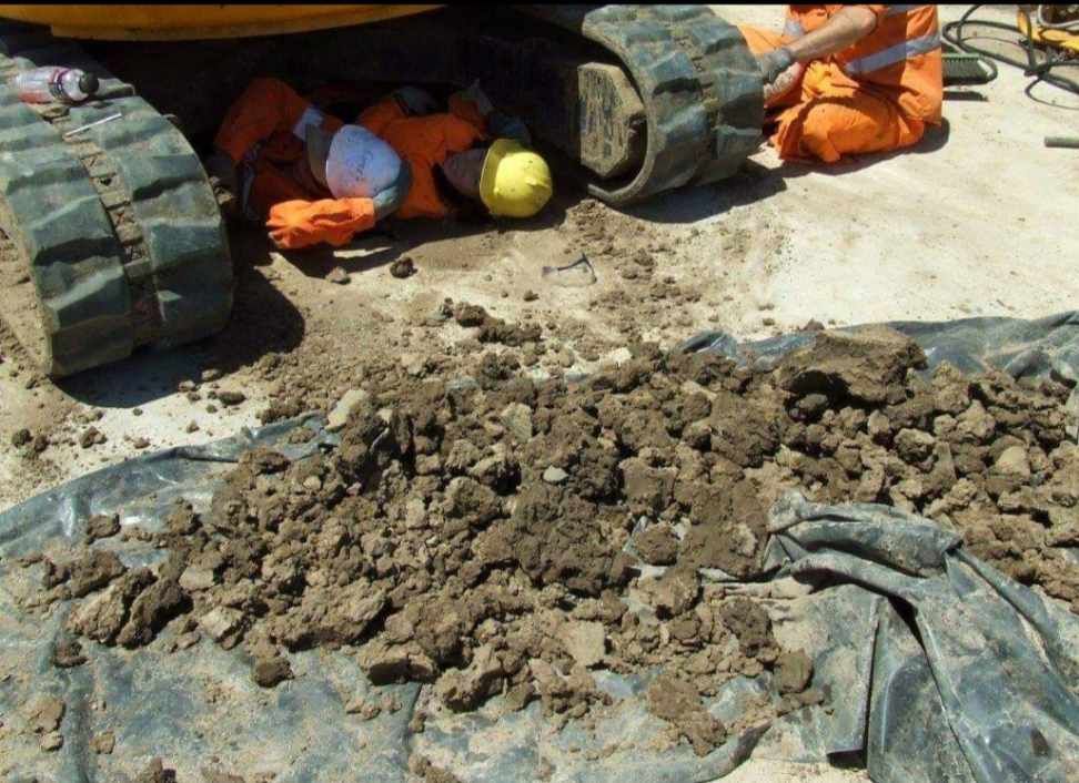 Man Is Laying In The Dirt Under A Construction Vehicle — Wetzler Pty Ltd In Marmor QLD