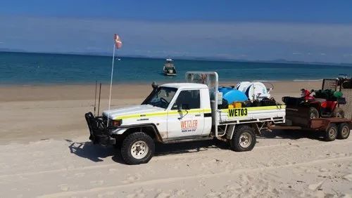 A White truck is Parked on the beach next to a Trailer — Wetzler Pty Ltd In Marmor QLD