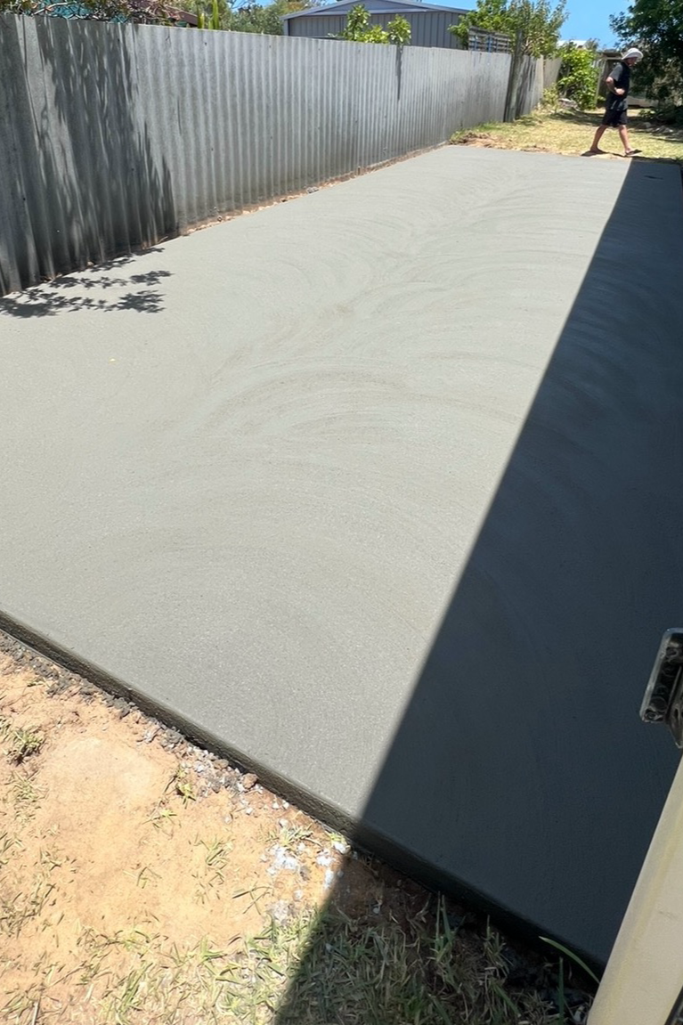 White pebble driveway leading to a red-roofed suburban house under a clear blue sky