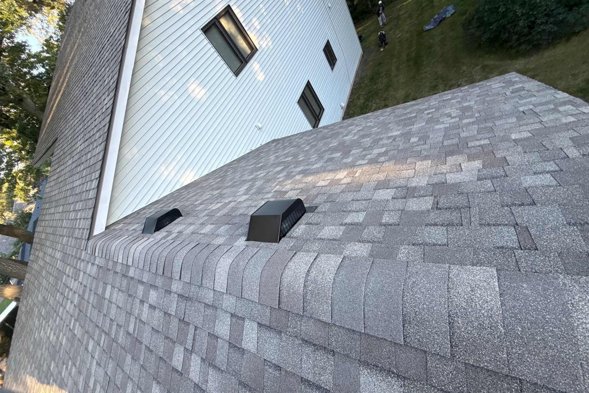 Gray asphalt shingle roof with two black roof vents on a residential home in Brooklyn Park, MN, show