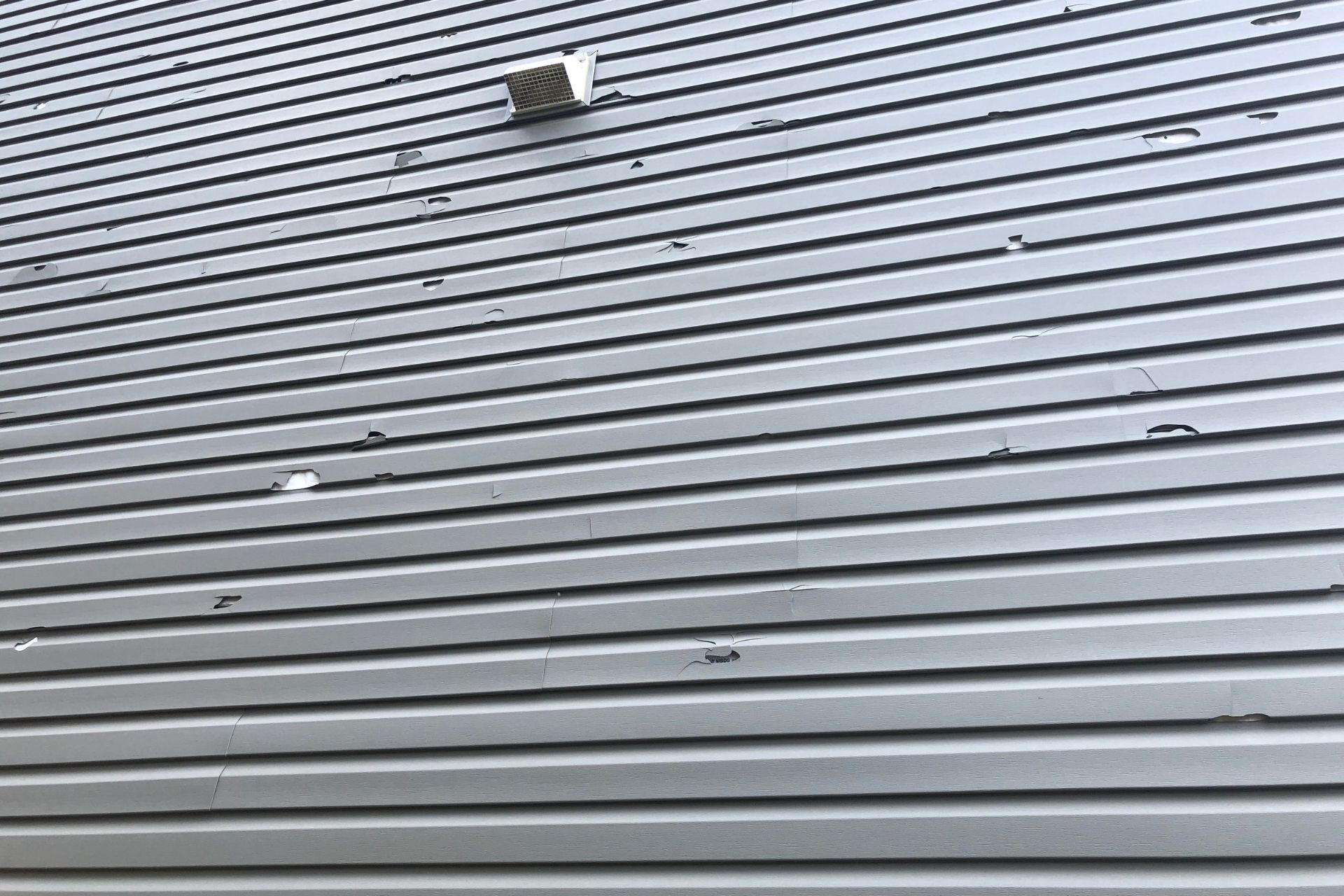Minnesota home after a hail and wind storm, with a homeowner checking for visible exterior damage.