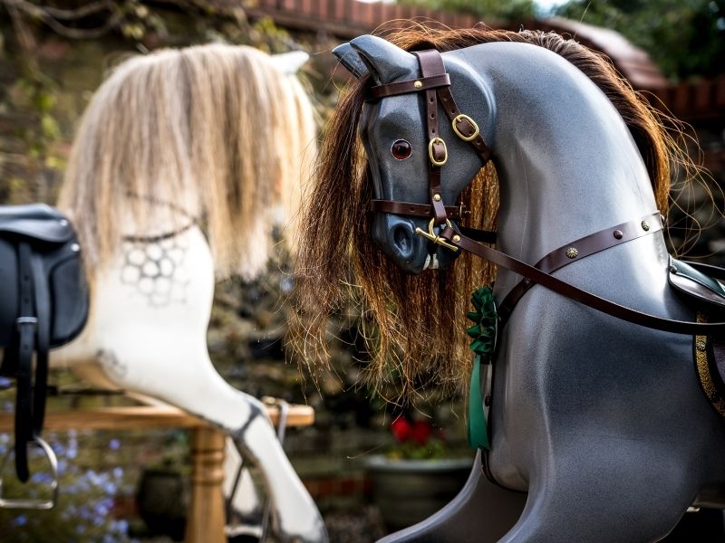 Gray rocking horse with black harness beside a white rocking horse