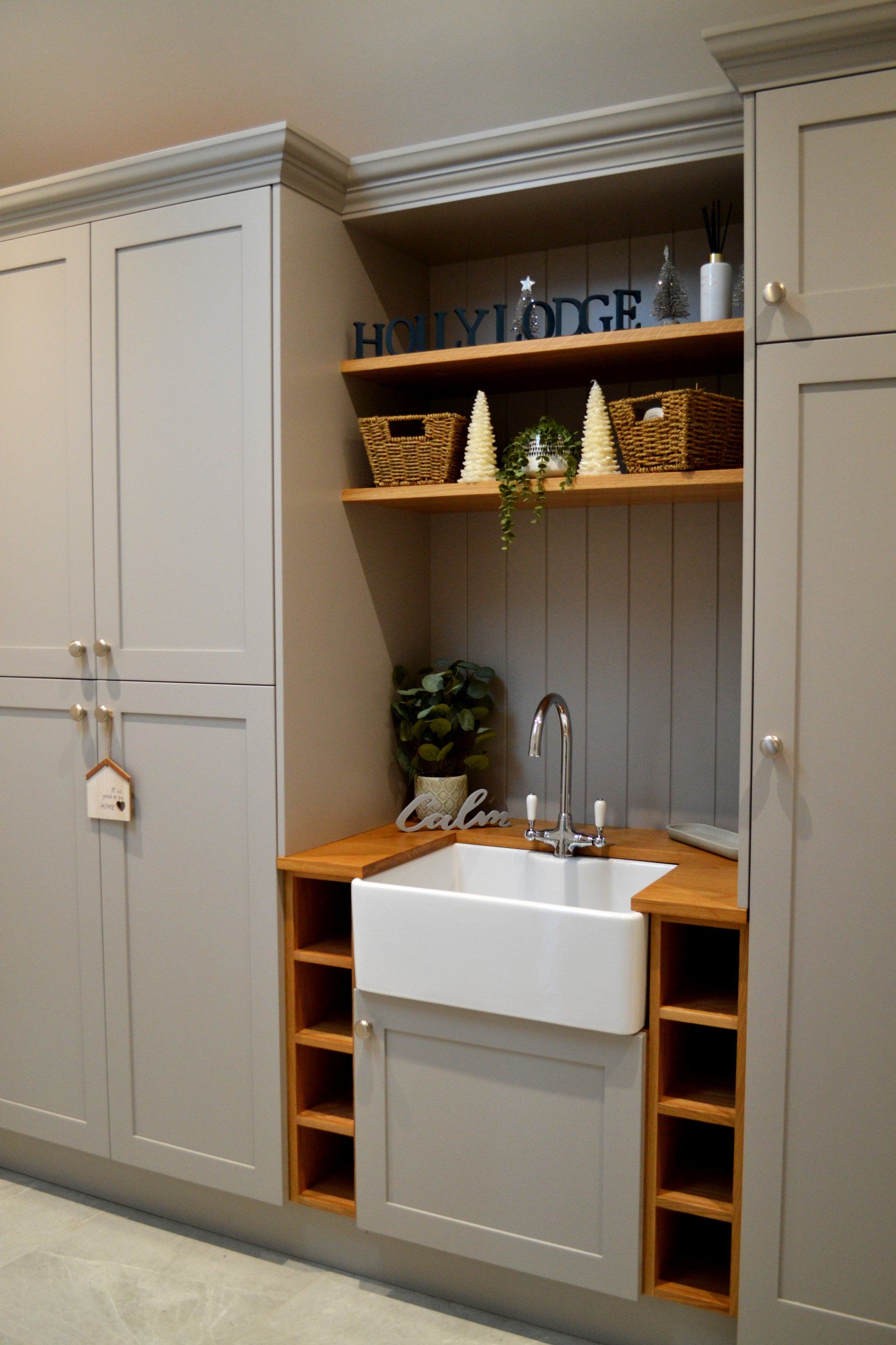 White built-in laundry nook with sink, shelves, woven baskets, and beige cabinets