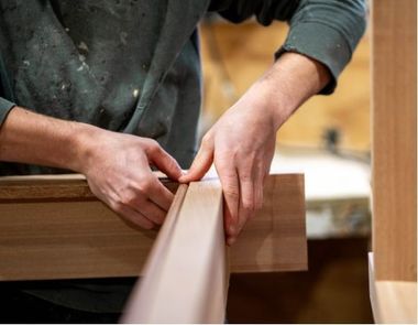 Hands measuring and aligning a wooden board in a workshop