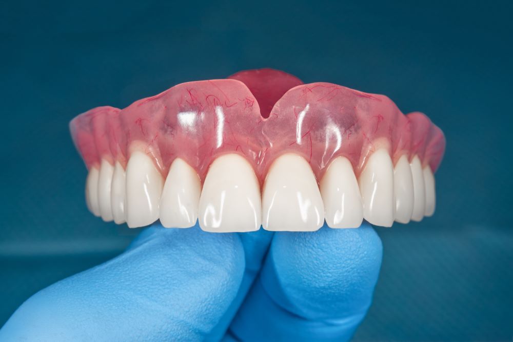 A Person is Holding a Full Denture in Their Hand — The Denture Kitchen in Maroochydore, QLD