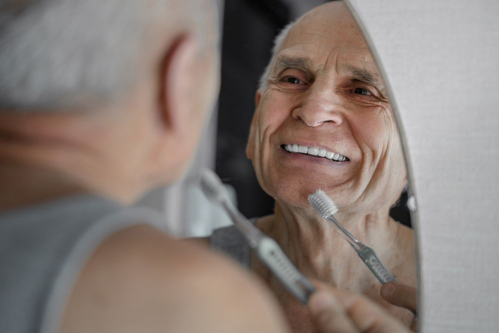 Elderly Man Smiling at The Mirror After Getting Dentures