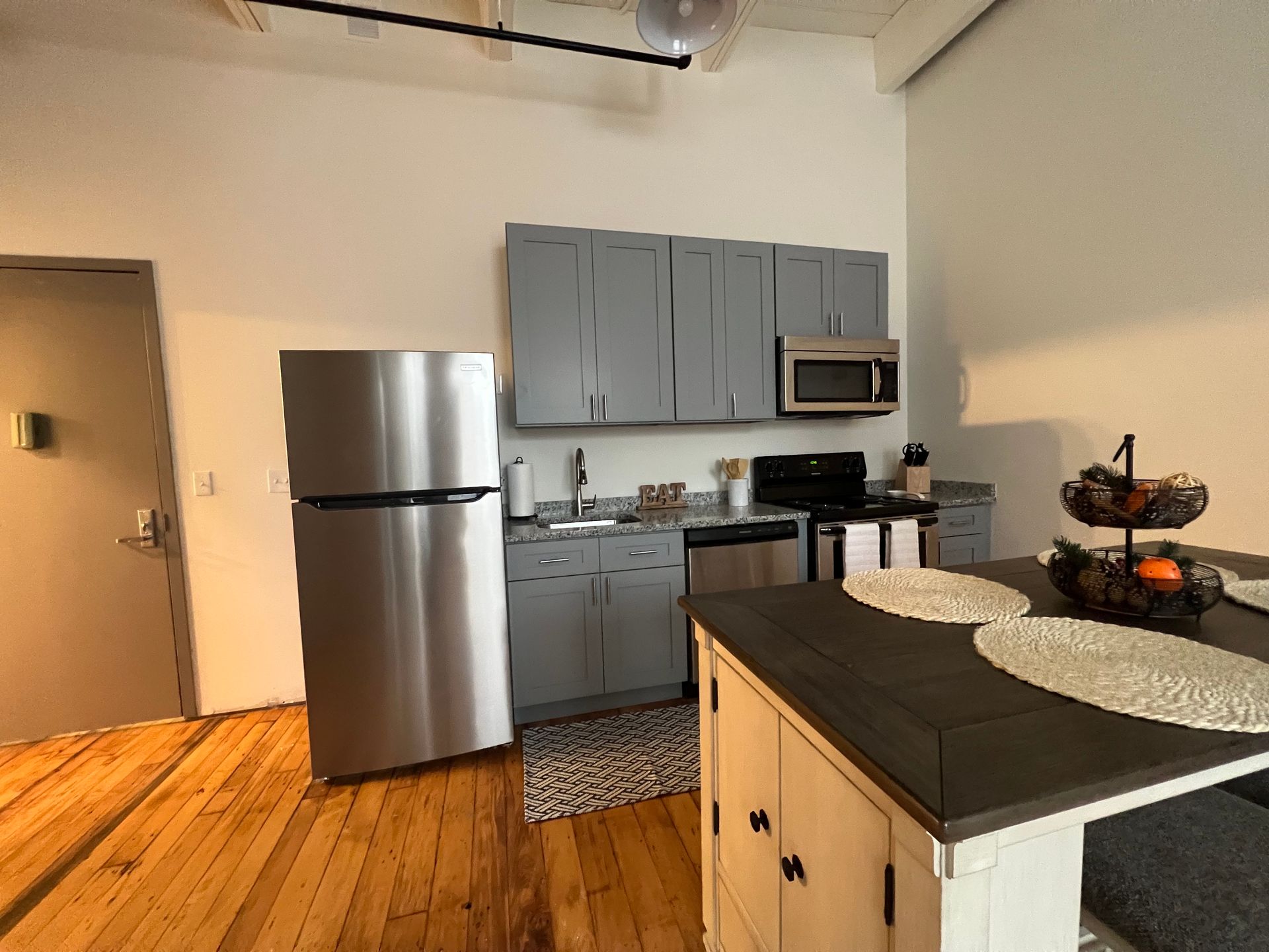 Kitchen with gray cabinets, stainless steel appliances, and wood floor.