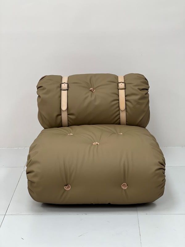 Olive-green, tufted floor cushion chair with a roll-up back and light brown straps and buttons.