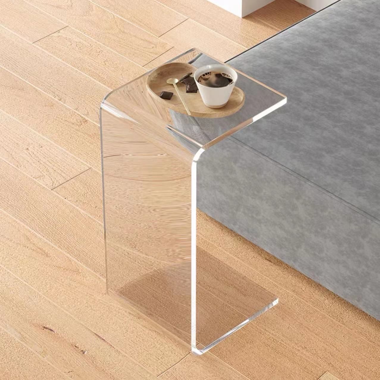 Clear acrylic C-shaped side table with a cup of coffee and a wooden tray.