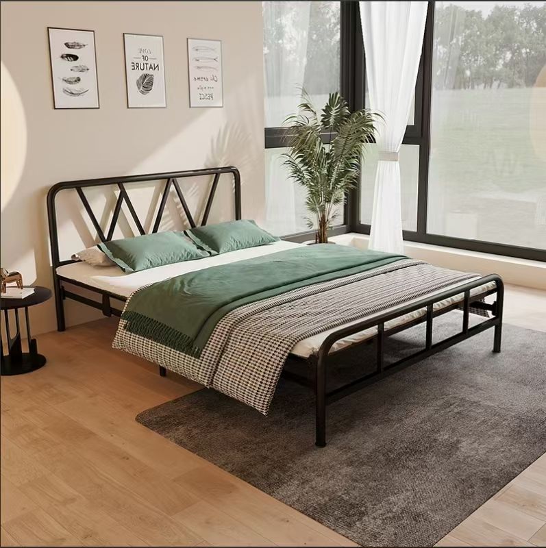 Black metal bed frame with green and white bedding in a bright bedroom.
