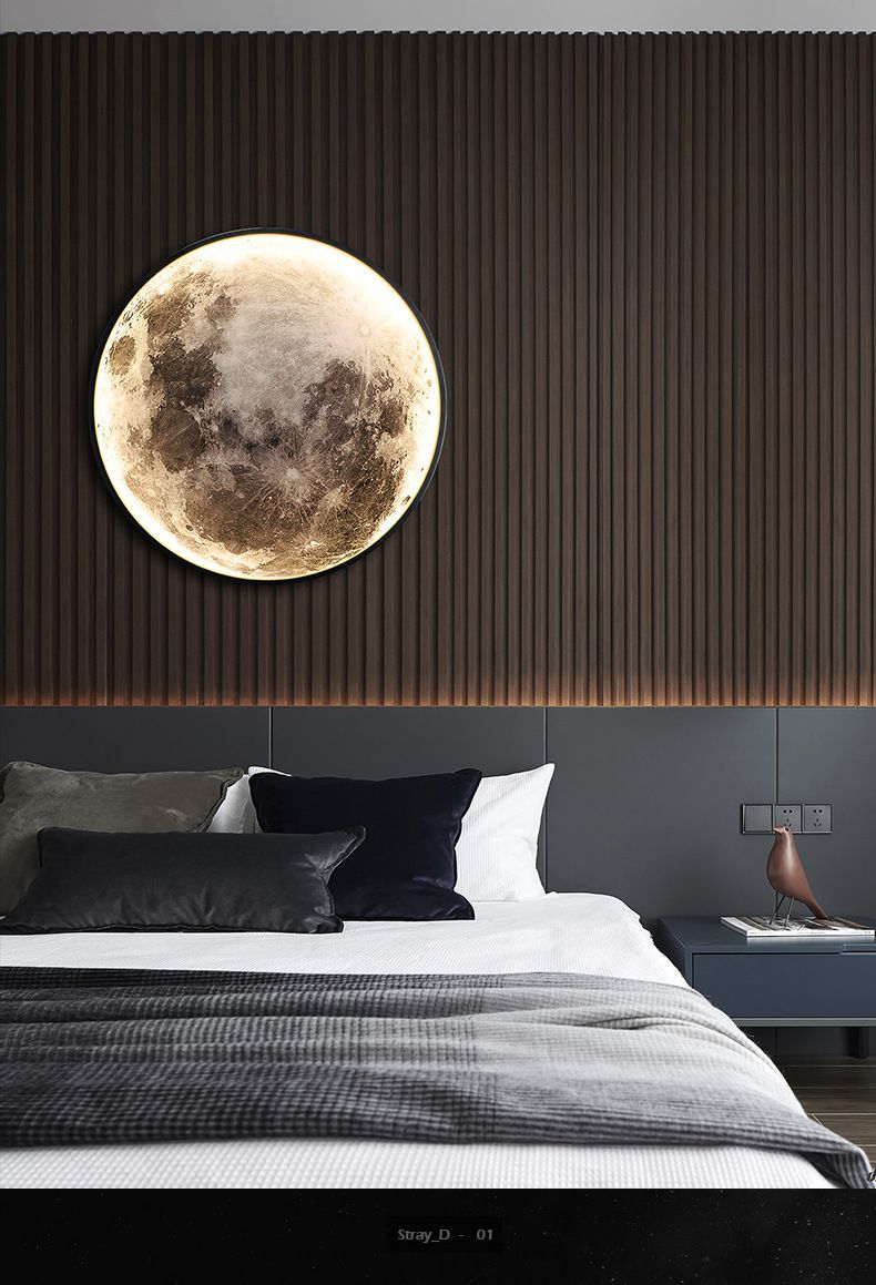 Bedroom with a moon-shaped wall lamp above the bed, dark wood paneling, and blue bedding.