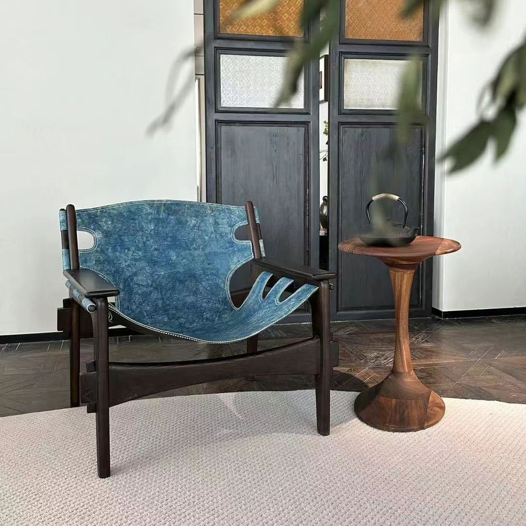 Blue upholstered chair and wooden side table next to dark wooden doors, on a white rug.