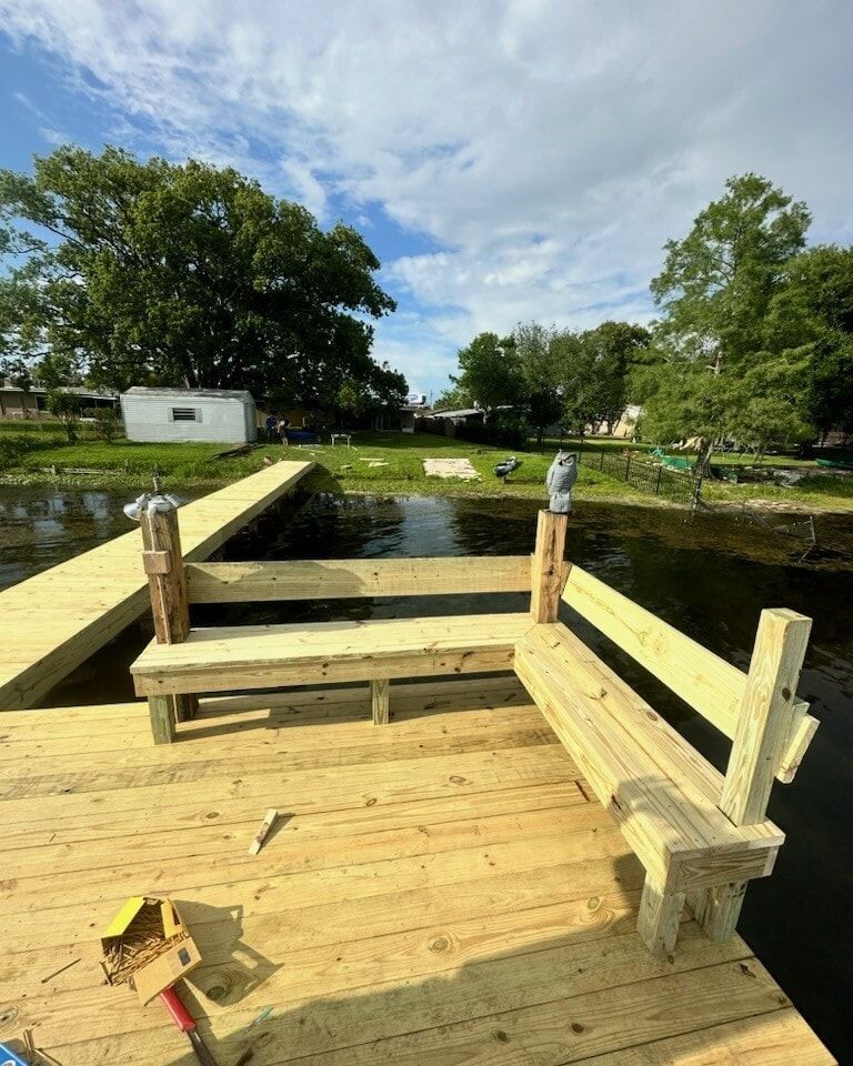 A newly built wooden dock with a bench, on a lake, under a cloudy sky.