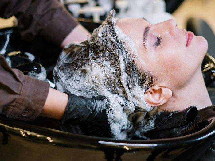 A woman is getting her hair washed in a sink at a salon.
