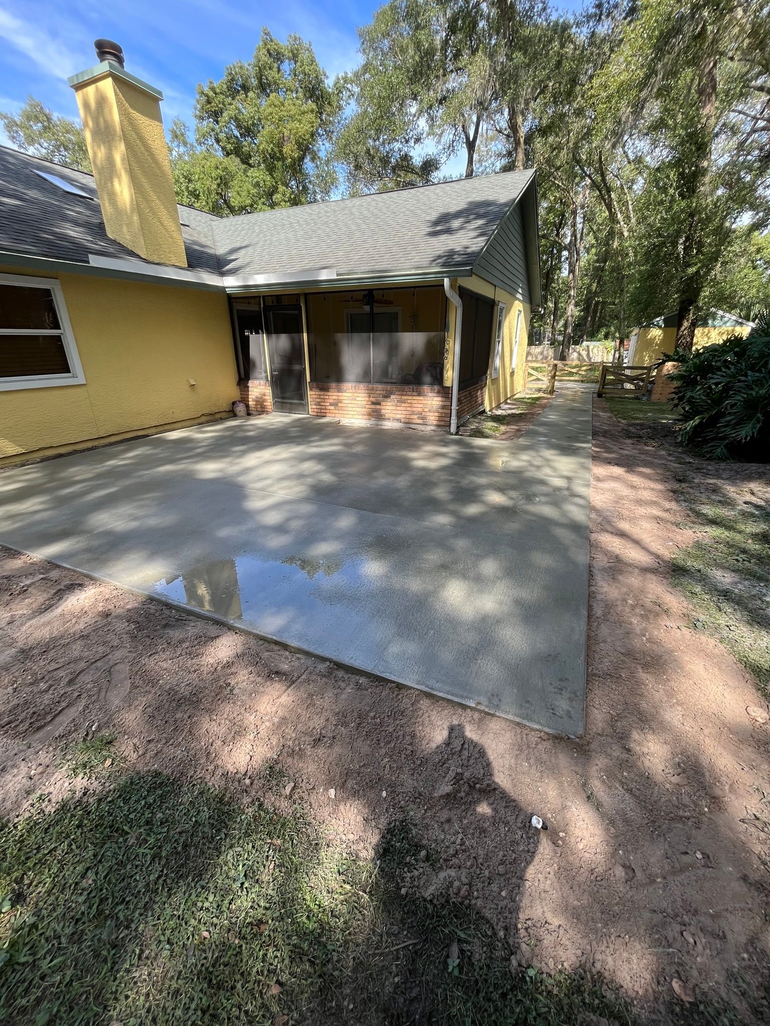 A yellow house with a concrete driveway in front of it.