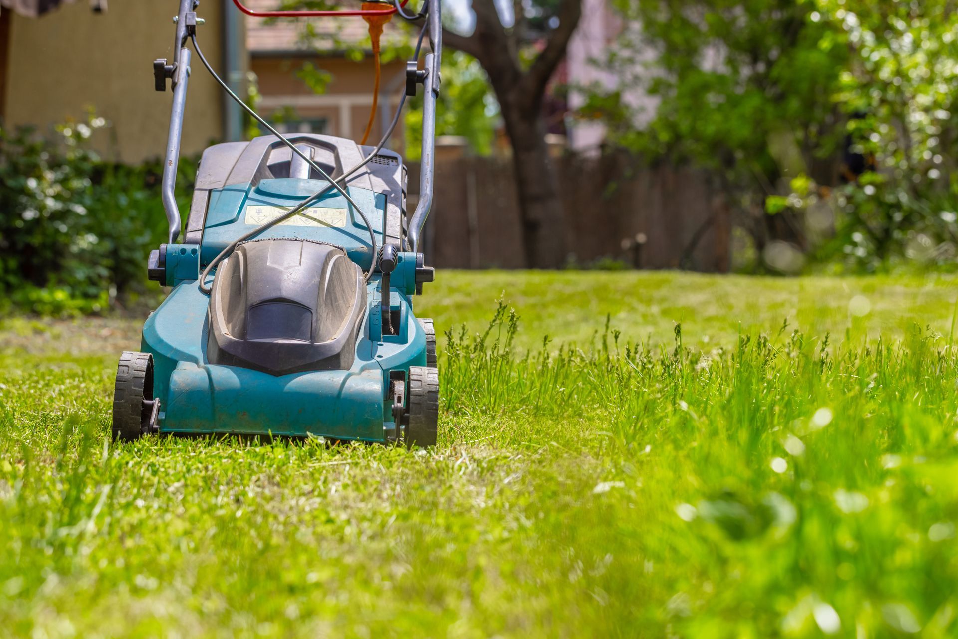 A lawn mower is cutting the grass in a backyard.
