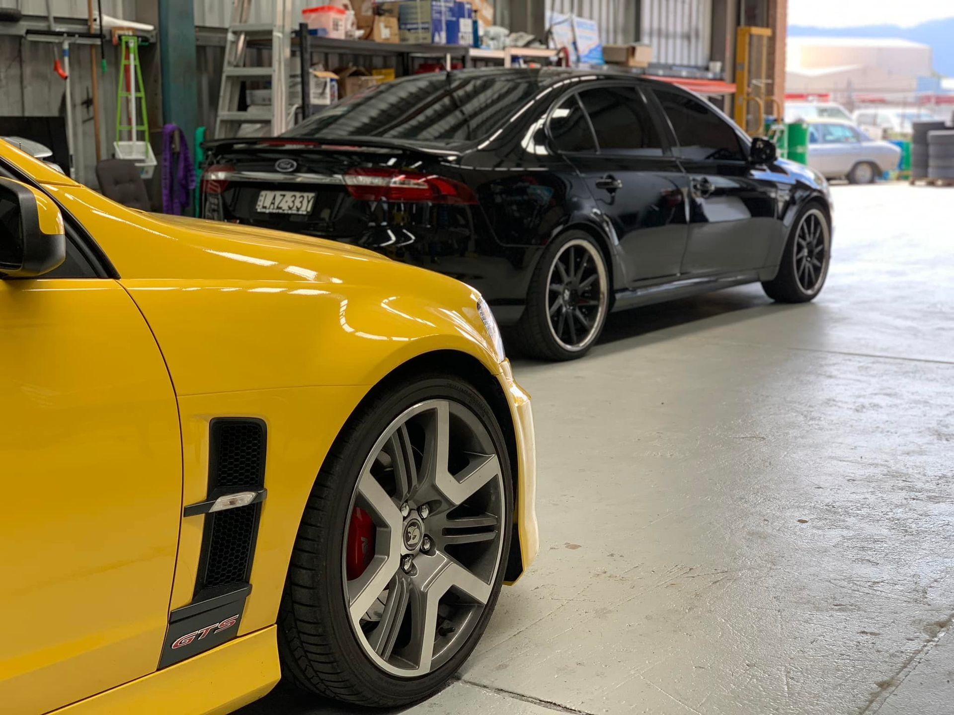 Yellow Sports Car Beside a Black Sedan Inside a Garage — D.A.G Automotive in Unanderra, NSW