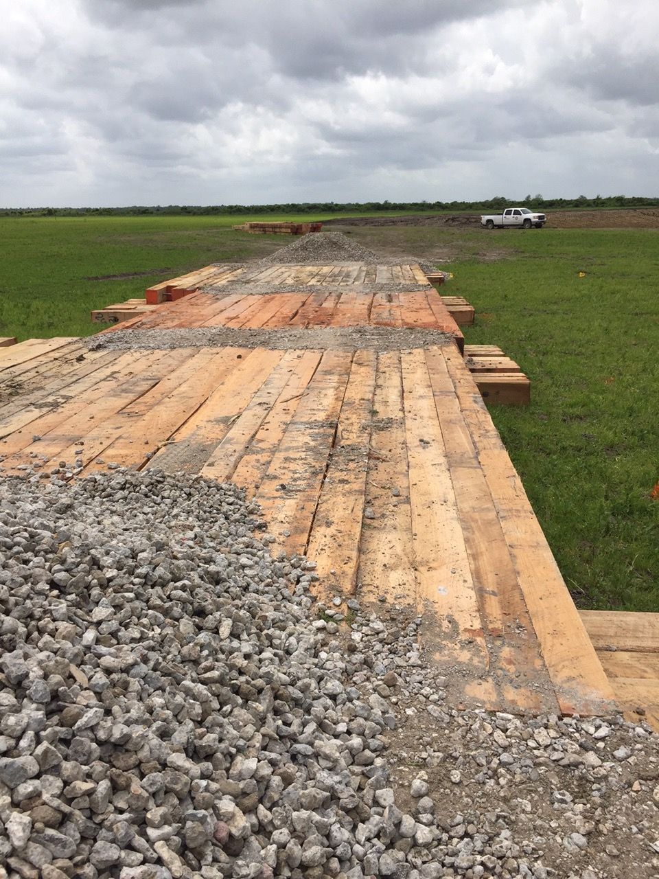 Air bridge planks laid across a muddy field under a cloudy sky