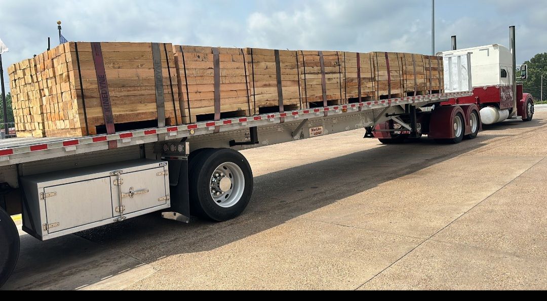 Flatbed truck hauling skids nationwide on a road under a cloudy sky