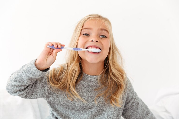 young girls brushing large fake tooth with yellow toothbrush