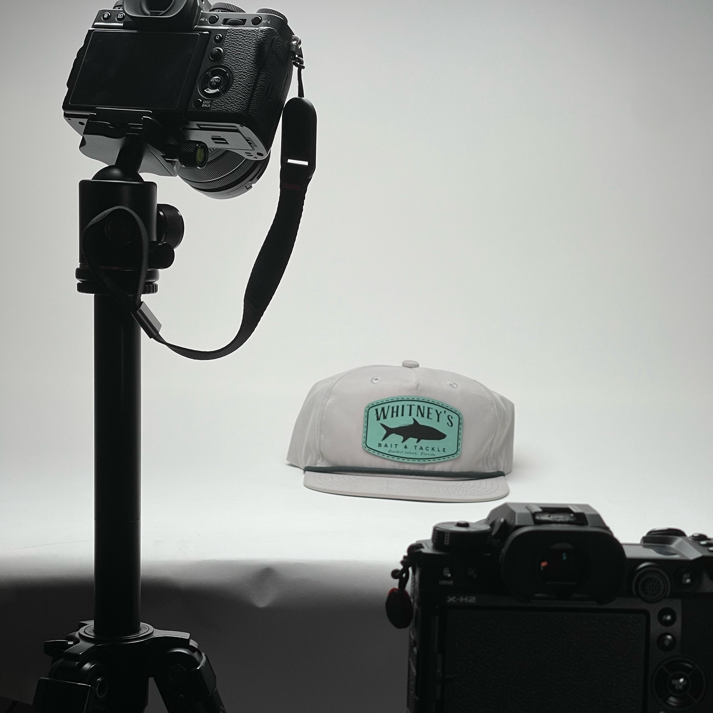 A camera is taking a picture of a hat with a fish on it
