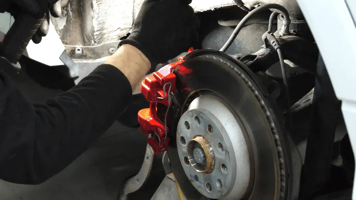 Mechanic repairing a car disc brake system in a shop