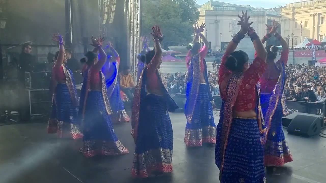 Garba dancers under stage lights in front of a large crowd