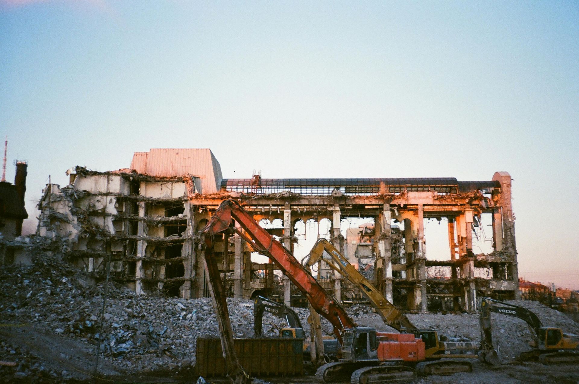 Building demolition with excavators, rubble, and a dusky sky.