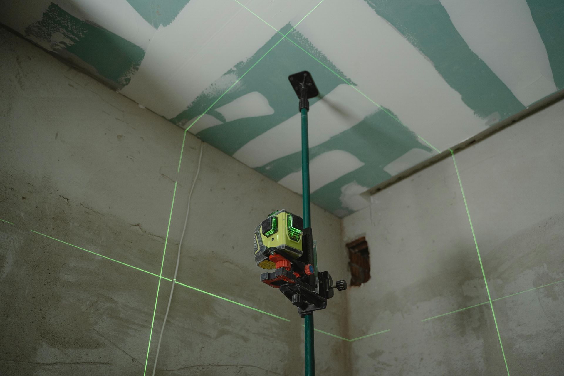 Green laser level projecting lines on walls and ceiling during construction.
