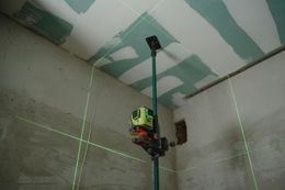 Green laser level projecting lines on walls and ceiling during construction.