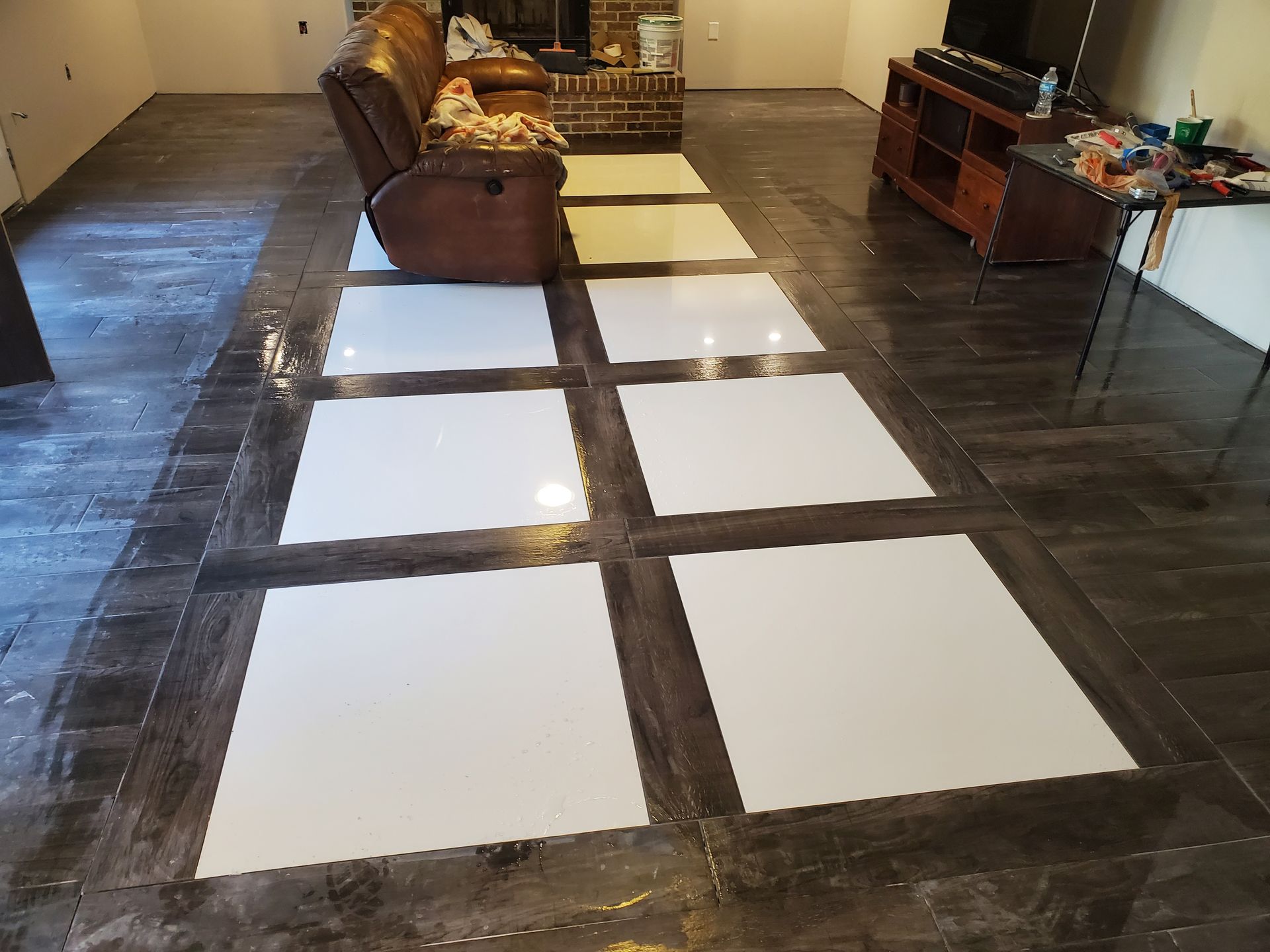 A living room with a couch , television , fireplace and white tiles on the floor.