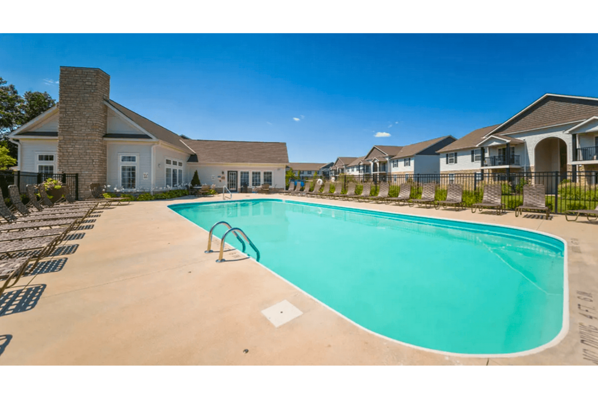 Apartment complex swimming pool with turquoise water, lounge chairs, and a sunny courtyard
