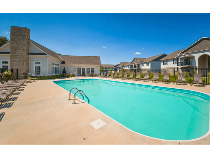 Outdoor swimming pool at a modern apartment complex under a clear blue sky